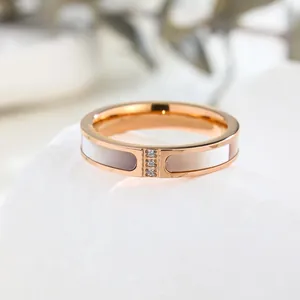 Primo piano di un anello in oro rosa con tre diamanti e intarsio in conchiglia bianca