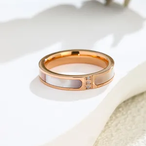 Primo piano macro di un anello in oro rosa con tre diamanti e intarsi di conchiglia