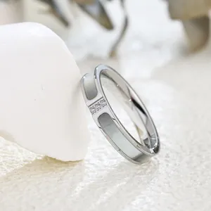 Dettaglio ravvicinato di un anello in argento minimalista con tre diamanti e intarsio in conchiglia.