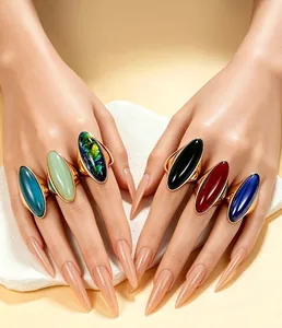 Gros plan détaillé de bagues en cristal vintage colorées sur des mains aux longs ongles