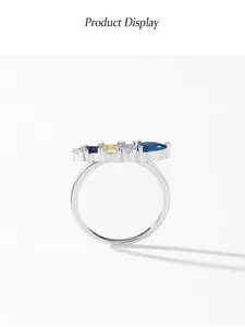 Primo piano di un anello d'argento con una fila di pietre preziose geometriche colorate