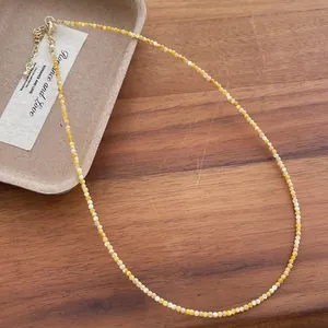 Detail view of 2mm yellow natural shell pearl choker necklace on wooden background