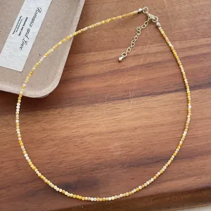 Detailed macro view of a 2mm natural yellow shell bead necklace with extender chain