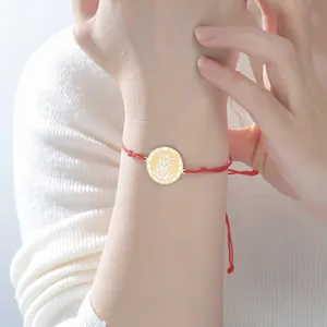 Vue détaillée du médaillon Saint Michel sur un bracelet en fil rouge porté au poignet