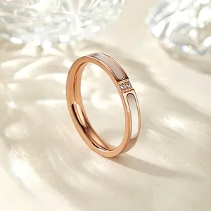 Vista detallada de un anillo de acero de titanio oro rosa con nácar blanco y pequeñas piedras.
