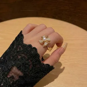 Nahaufnahme eines goldenen Blumenrings mit Perle und Zirkonia am Finger