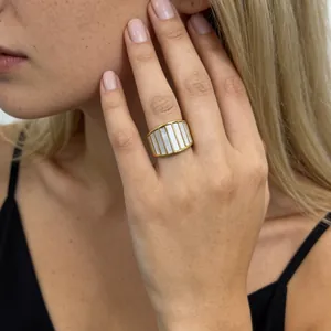 Detailopname van een brede gouden titanium ring met prachtige witte parelmoer inlays op vinger.