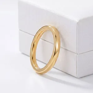 A high-quality close-up of a minimalist polished gold stainless steel ring on a white box