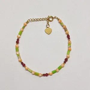 Close-up of bohemian handmade beaded bracelet with heart charm and gold-tone clasp