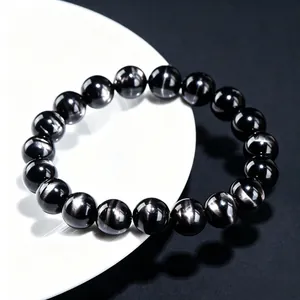 Handmade natural black bronzite beaded bracelet with metallic golden sheen on a white plate