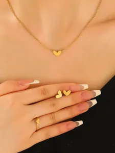 Detailed view of a gold-colored heart pendant necklace, stud earrings, and ring set.