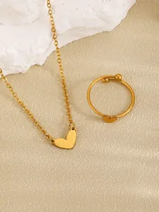 Macro view of golden stainless steel necklace and ring set featuring smooth heart pendant