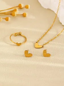 Close-up view of a minimalist golden heart jewelry set with necklace, ring and earrings.