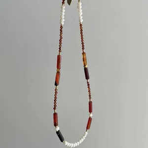 Detailed view of vintage natural stone and pearl beaded necklace with an earthy color palette