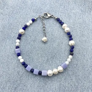 Detail view of mixed natural stone beaded bracelet with pearls and lapis on denim