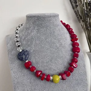 Detail of vintage beaded necklace with red natural stones and blue heart pendant.
