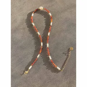 Close-up of orange natural stone beaded necklace with pearl detail and gold-tone chain