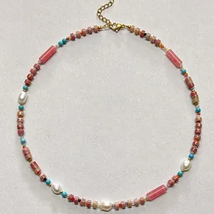 Macro detail of a vintage beaded necklace featuring pink rhodonite beads and baroque pearls