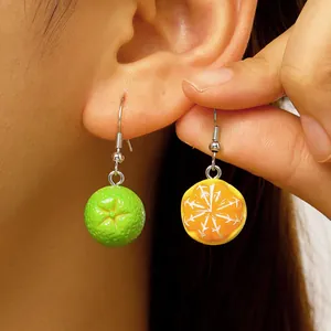 Macro detail of 3D resin fruit earrings featuring cute green and orange orange slices
