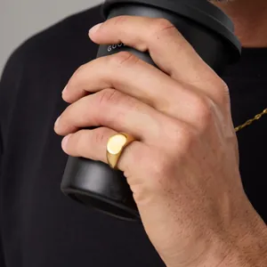 Detalle de primer plano de un anillo de sello minimalista de acero inoxidable dorado en un dedo