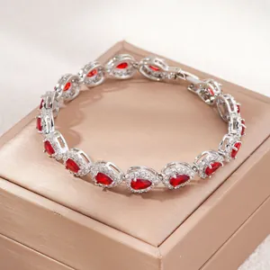 Dettaglio di un bracciale con zirconi rossi a goccia esposto su una scatola per gioielli.