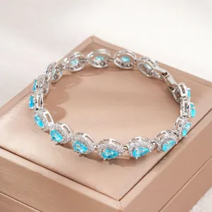 Primo piano di un bracciale in argento con pietre di zirconia blu a forma di goccia.
