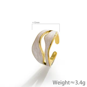 Dettaglio anello dorato ondulato con smalto bianco marmorizzato e dimensioni
