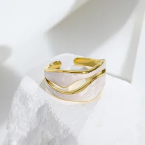 Primo piano di anello in acciaio al titanio con design a onde e smalto bianco marmorizzato