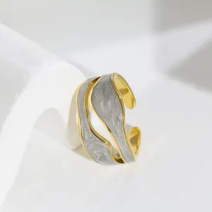 Primo piano di un anello dorato irregolare unico con intarsio in smalto grigio marmo