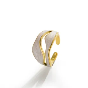 Vista dettagliata di un anello d'oro ondulato con elegante inserto in smalto bianco