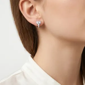 Primo piano di un orecchino a fiocco in argento con zirconi cubici sull'orecchio di una modella.