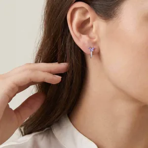Primo piano di un orecchino a farfalla viola con zirconi scintillanti sull'orecchio di una modella