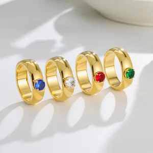 Close-up view of four gold titanium steel rings with colorful cubic zirconia