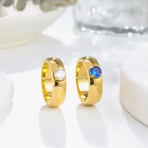 Detail view of two gold titanium steel rings featuring white and blue round zircons.