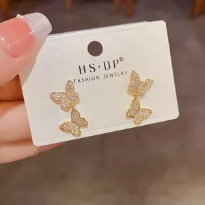 Detailed view of elegant gold butterfly drop earrings with sparkling crystals.
