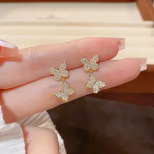 Macro detail of elegant double butterfly earrings with sparkling pavé crystals and gold.