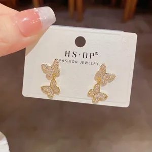 Macro detail of gold double butterfly earrings with tiny sparkling crystals.