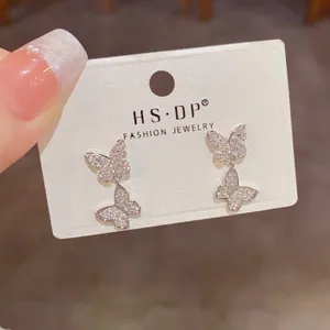 Close-up detail of sparkling double butterfly drop earrings with cubic zirconia inlay