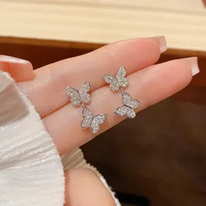 Detailed macro view of sparkling double butterfly dangling earrings encrusted with zircon.