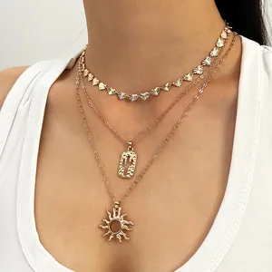Detailopname van een gelaagde vergulde ketting met bedeltjes van de zon en cactus