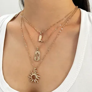 Detailopname van gouden meerlaagse halsketting met laars, cactus en zon hangers.
