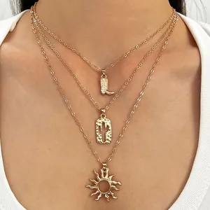 Detailweergave van een goudkleurige gelaagde ketting met laars-, cactus- en zonhangers.