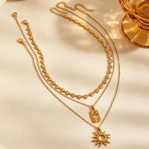 Detail van een vintage meerlagige gouden ketting met cactus- en zonnehangers in retrostijl