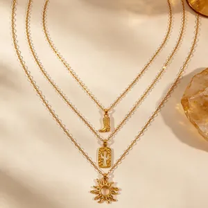 Detail van gelaagde gouden ketting met cowboylaars cactus en zon hangers macro weergave