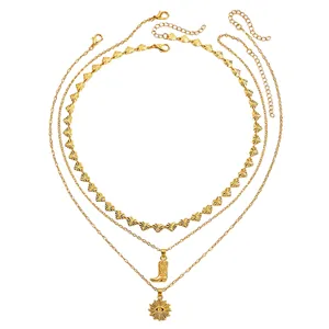 Detailopname van een gouden gelaagde ketting met westernlaars en zonoog hangers