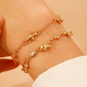 Detailansicht goldener Bettelarmbänder mit Schleifenmotiven und funkelnden Strasssteinen