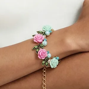 Vista detallada de una elegante pulsera floral con rosas rosas y perlas en la muñeca