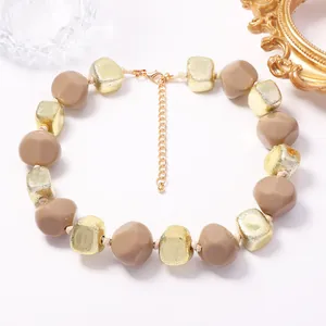 Détail de près des perles de résine géométriques kaki et dorées sur ce collier tendance