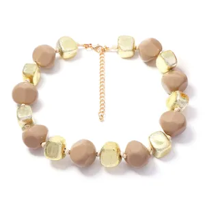 Vue détaillée d'un collier en perles de résine géométriques avec feuille d'or et cubes bruns.