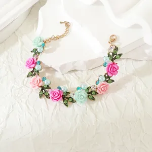Detalle de una pulsera floral con rosas de resina en tonos pastel y perlas sobre blanco